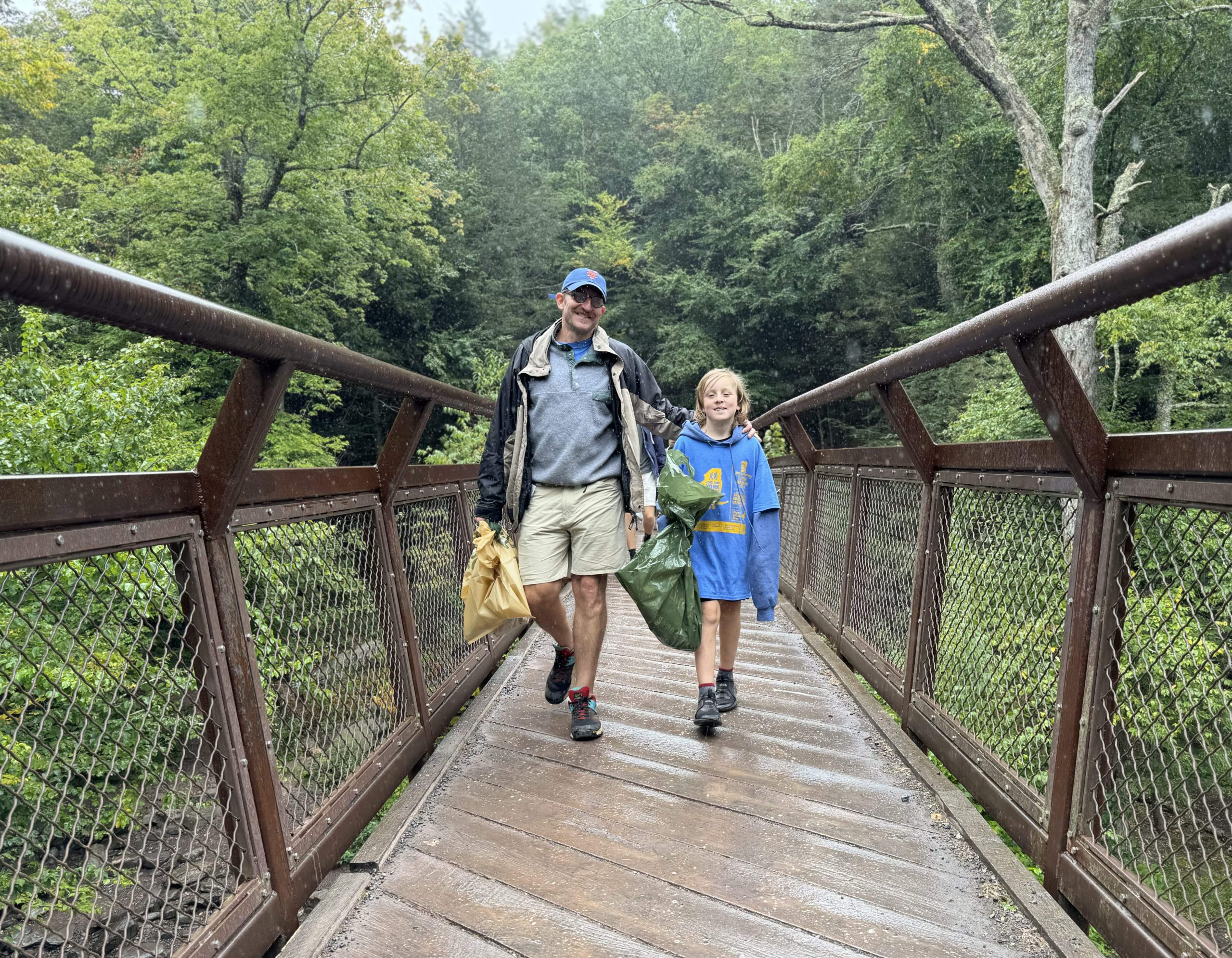 A man and a child walk alongside each other across a foot bridge.