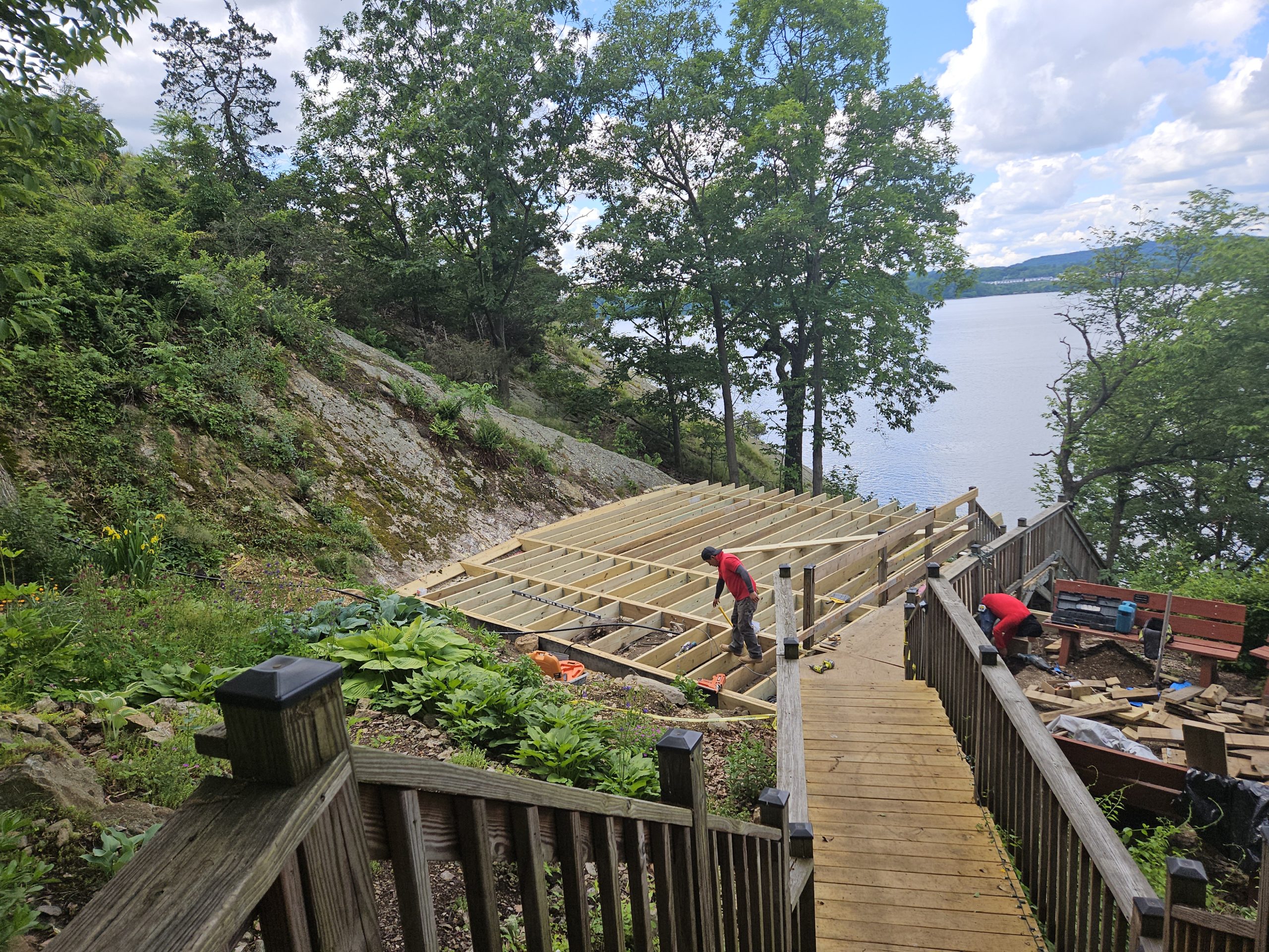 A man works to construct a deck along the water.