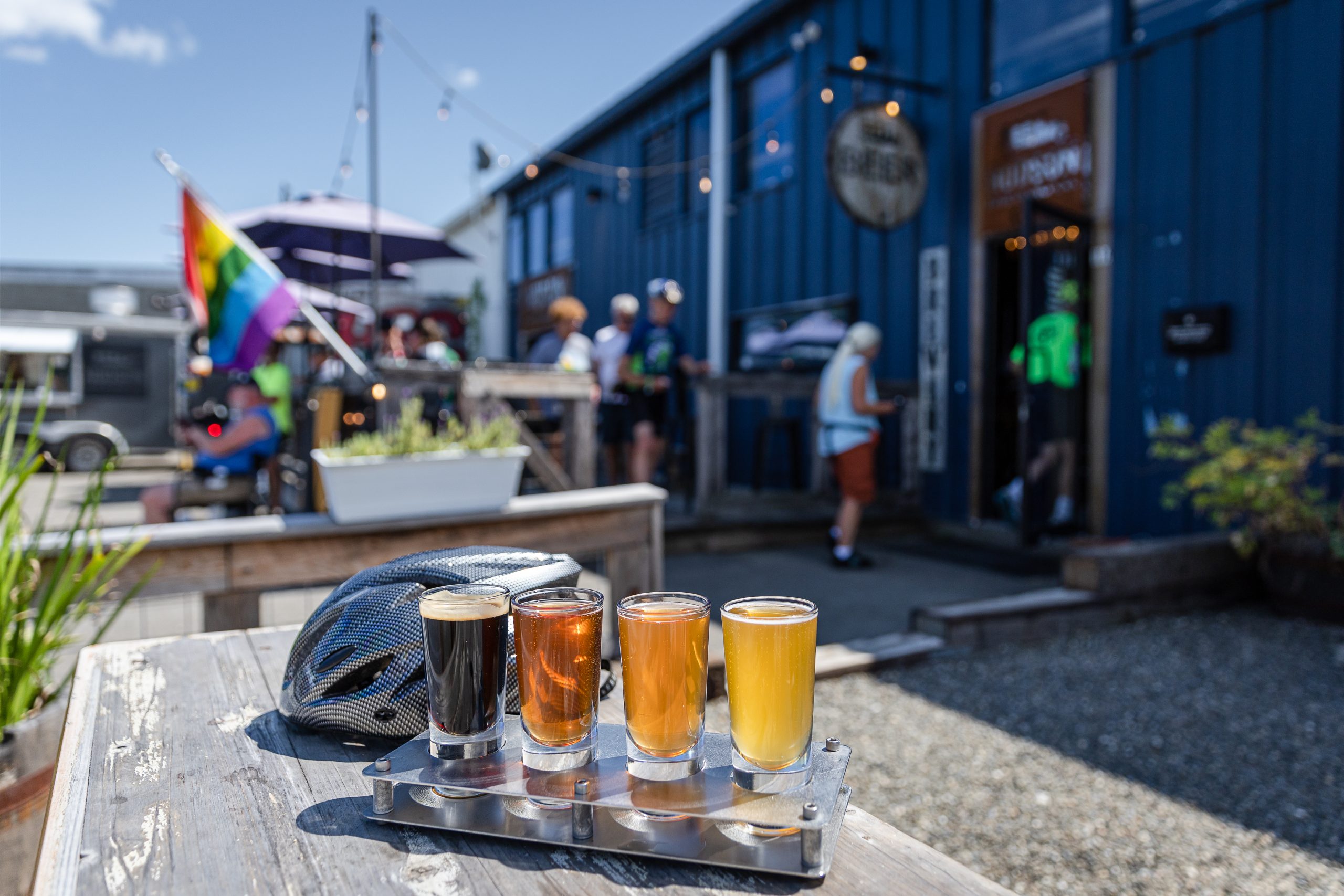 A flight of beers sits alongside a helmet at an outdoor brewery.