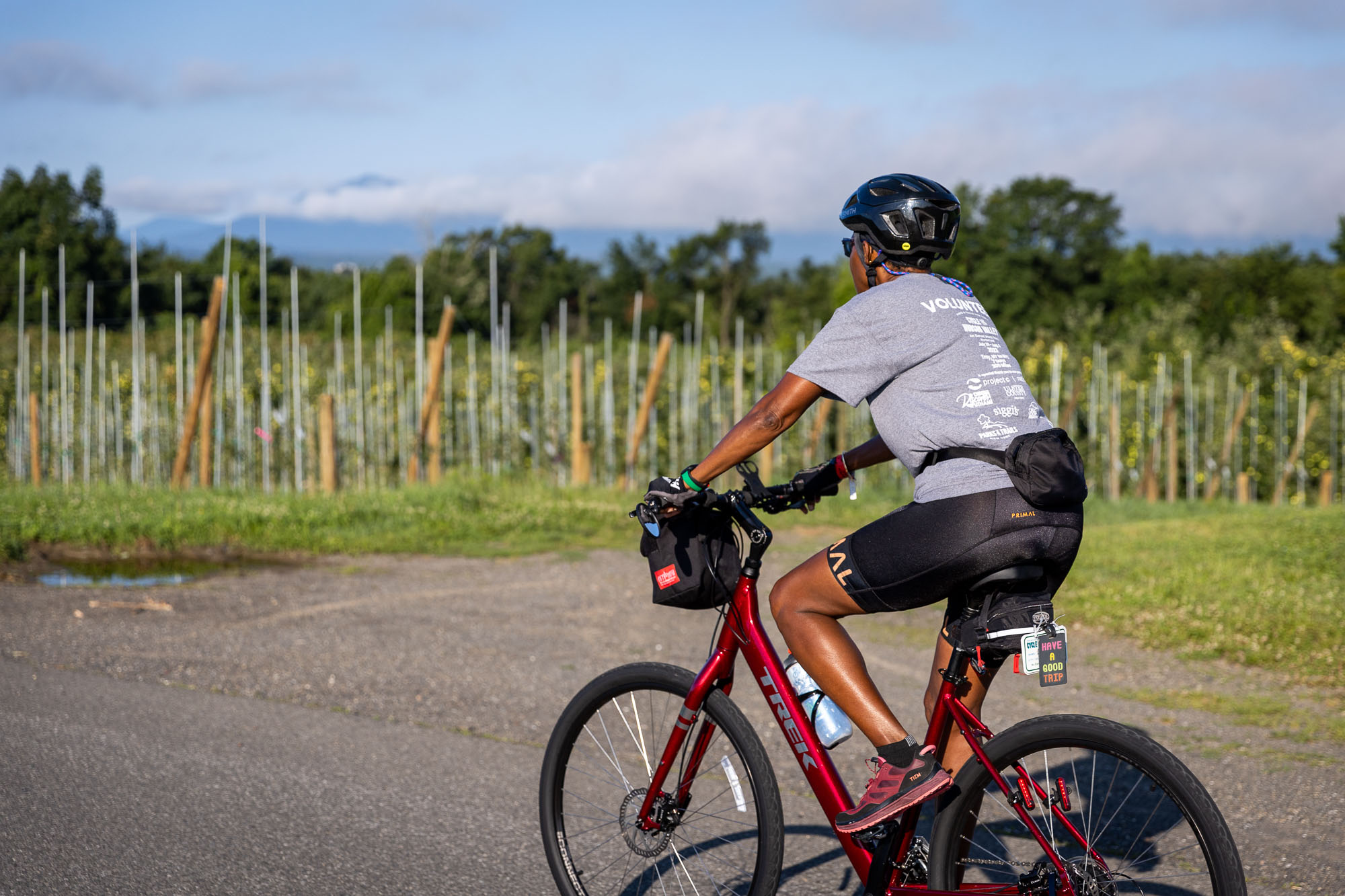 A Cycle the Erie Canal volunteer riding a red bicycle cycles along a country road in the Hudson Valley.