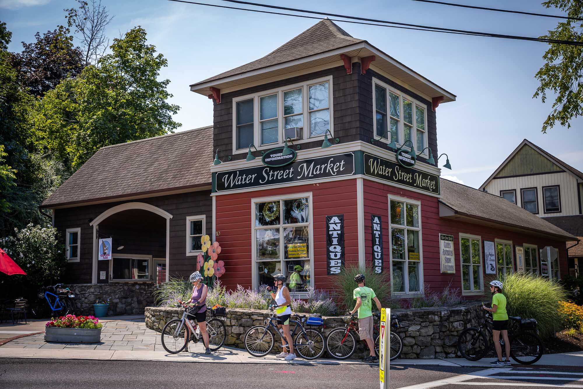 Three cyclists get on their bike outside of a local business called Water Street Market.