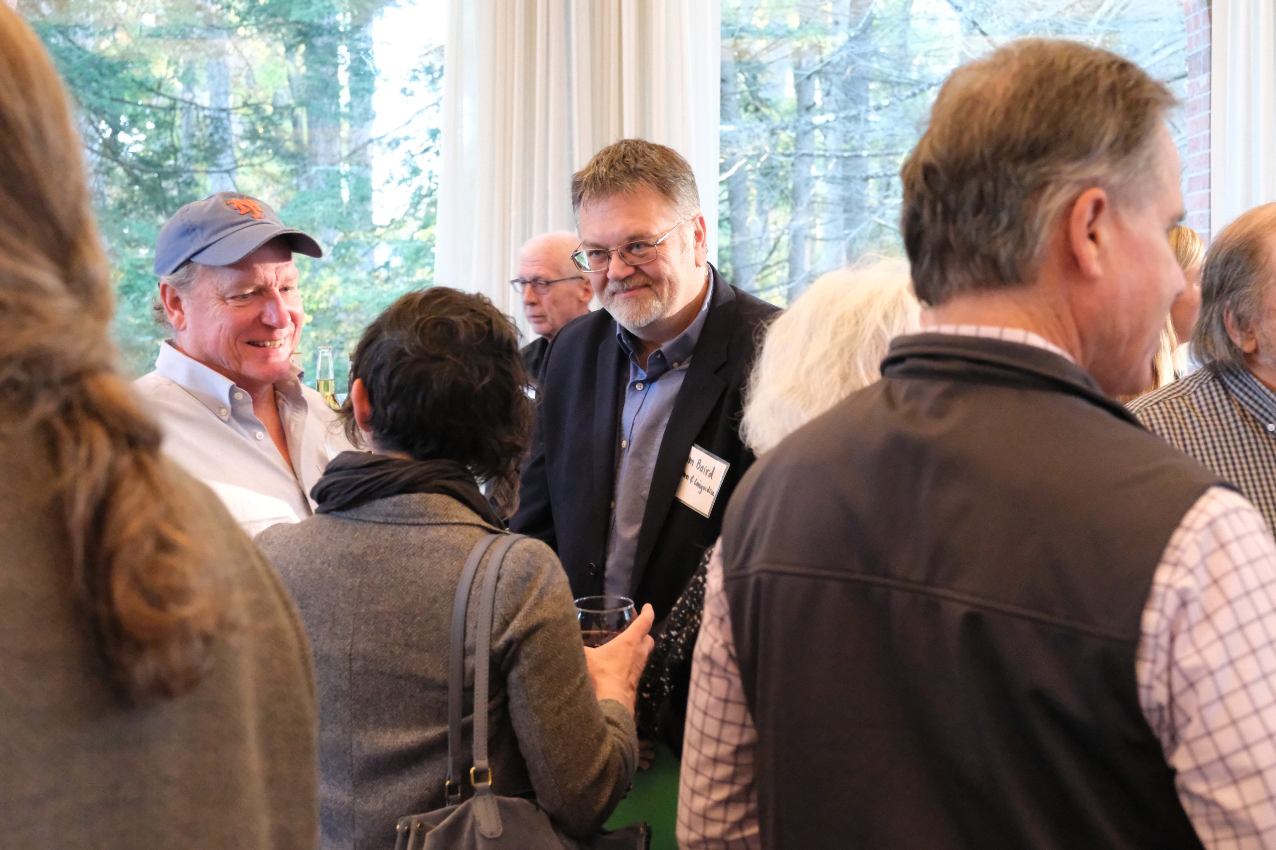 A crowded room of people speak to one another.