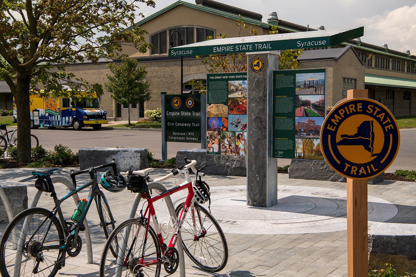 A bike rack full of bikes alongside an Empire State Trail sign and informational kiosk.
