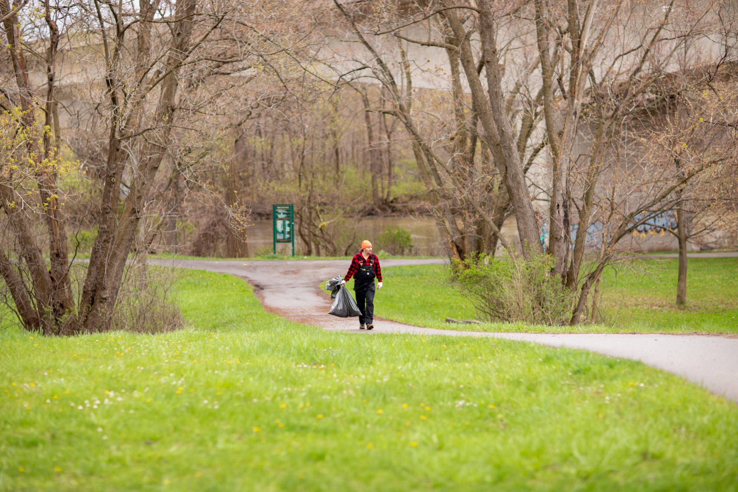 From a distance, a volunteer walks along a path picking up litter.