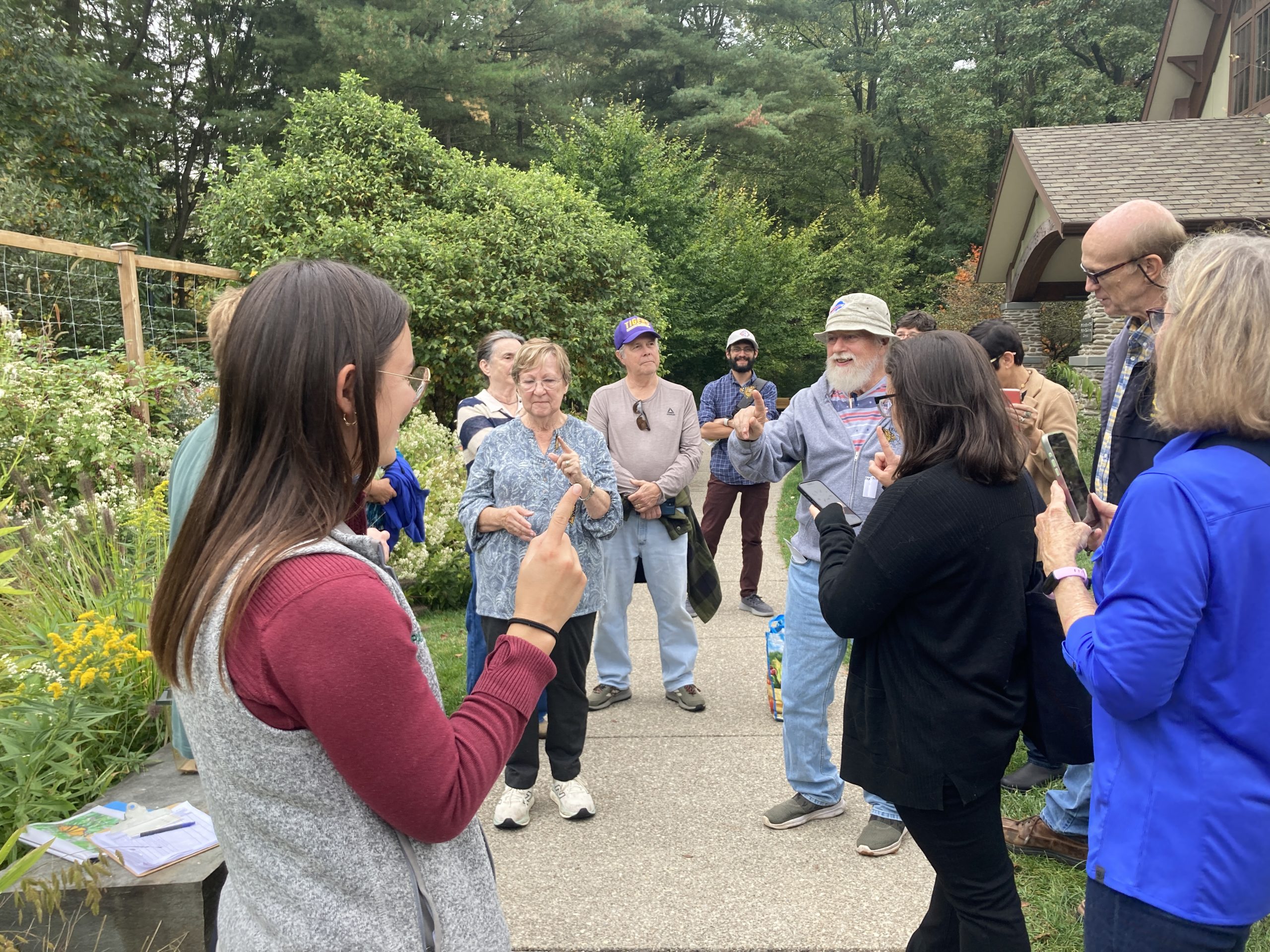 A group of people smile with their pointer fingers extended, hoping to catch a butterfly.