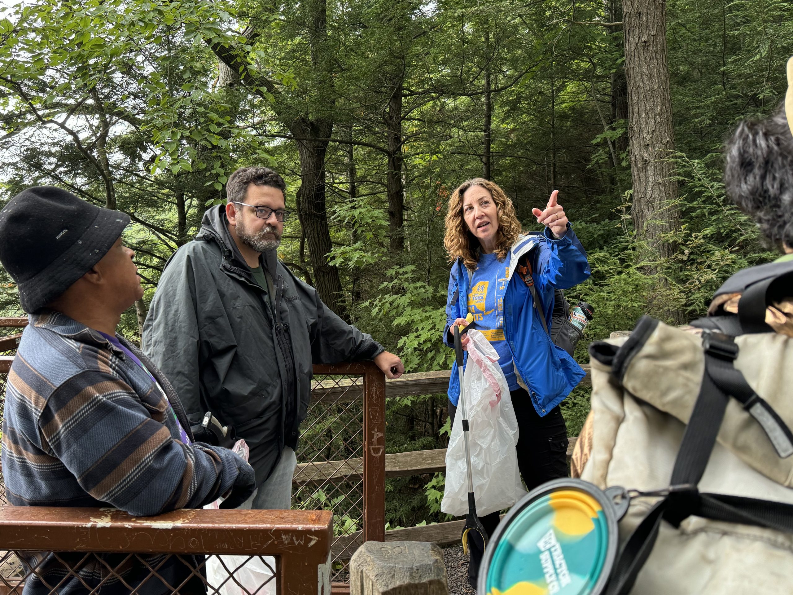 A woman points into the distance as a group of volunteers listen.
