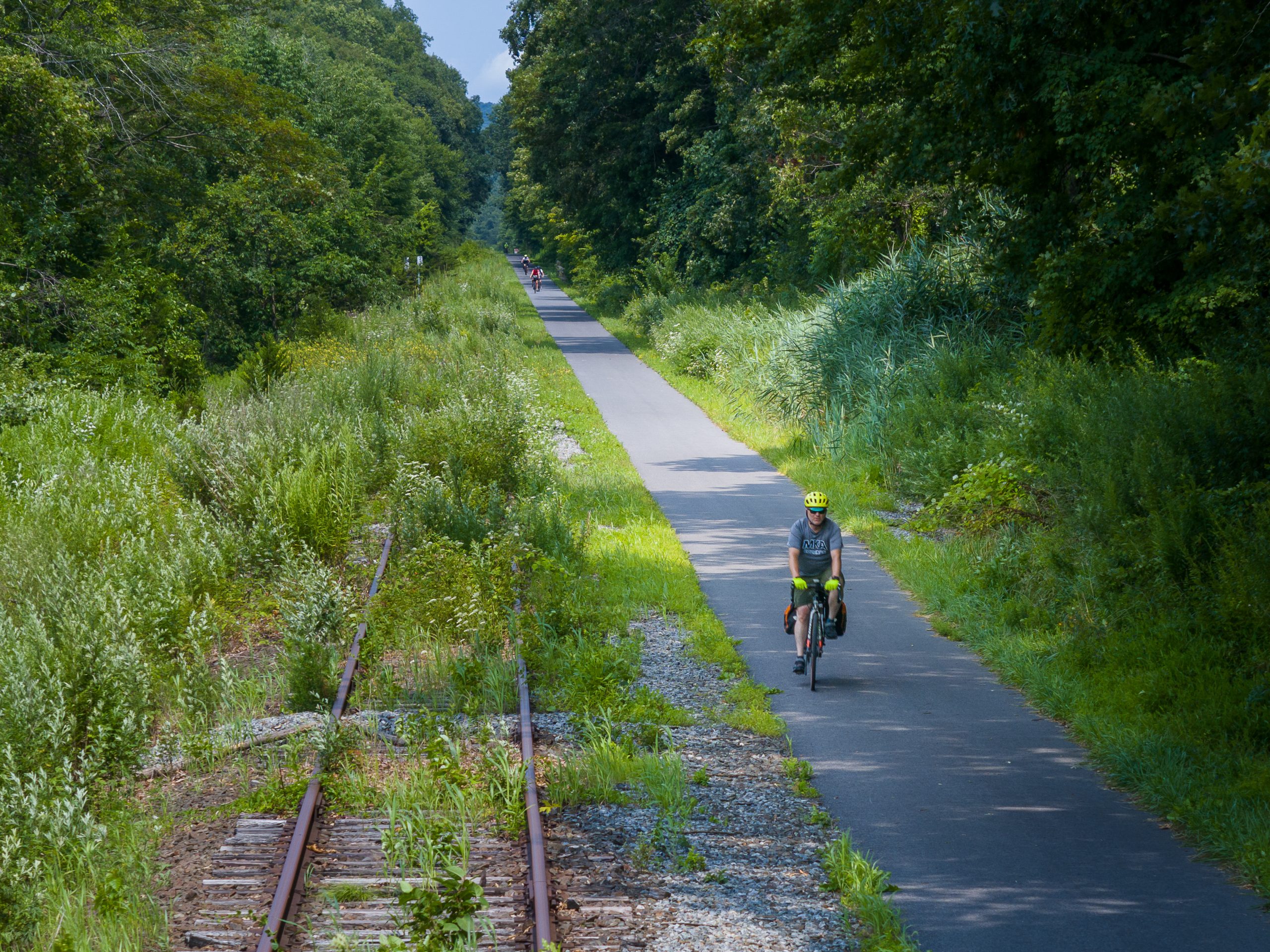 A cyclists rides alongside an inactive railroad.