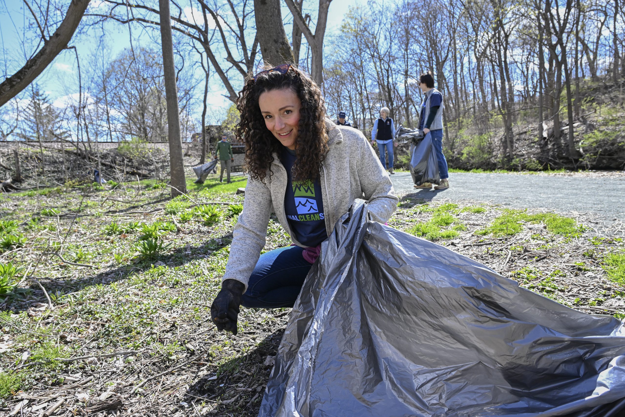 A volunteer holds a trash bag as she picks up litter along the Erie Canalway Trail.