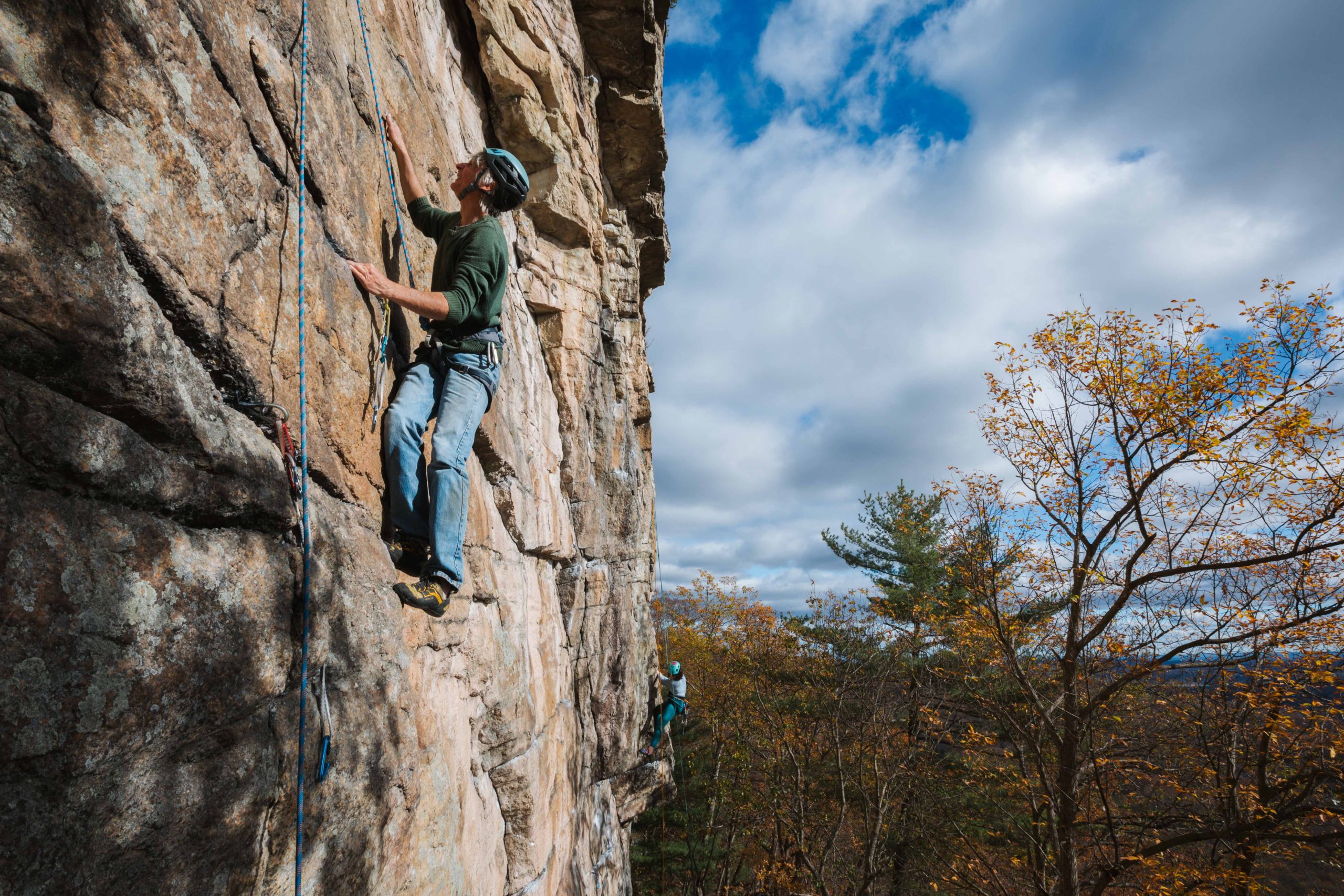 A man rock climbs on a fall day.