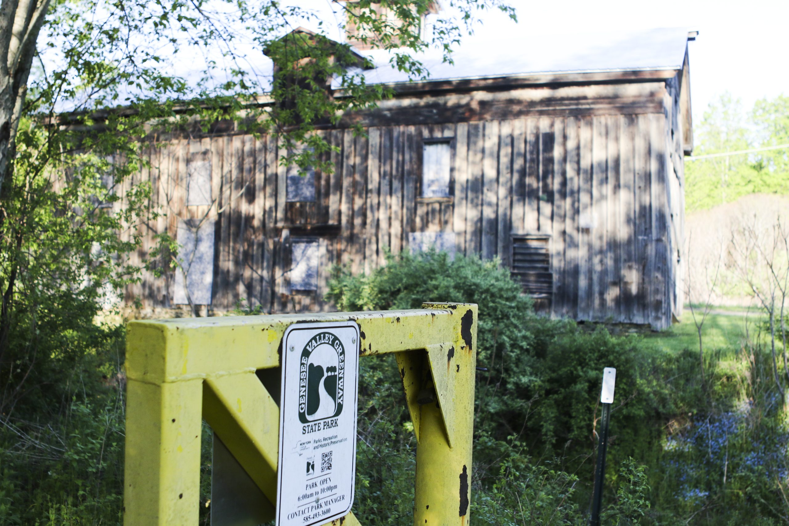 Belfast Canal Warehouse in background with Genesee Valley Greenway yellow gate in foreground.