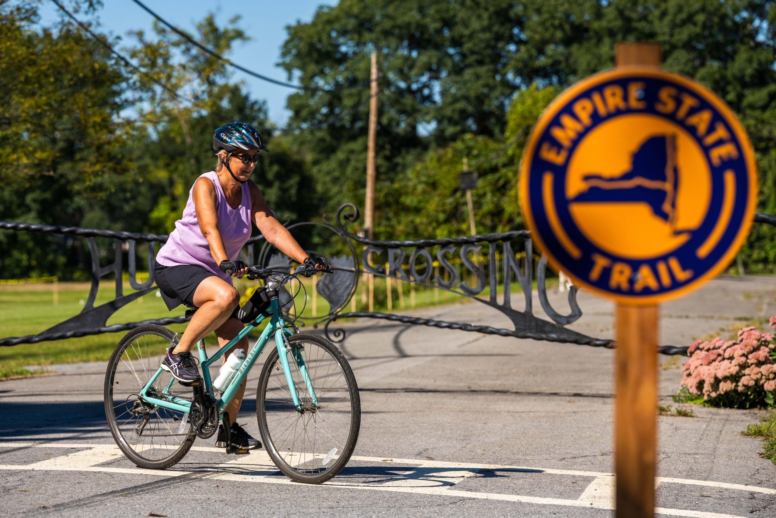 Cyclist riding in the background of an Empire State Trail sign.